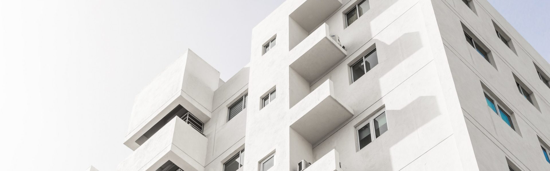 A low angle shot of a facade of a white modern building under a blue clear sky